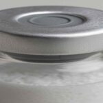 Aluminum crimp seal defect on lyophilized vial under visual inspection for GMP quality assurance.